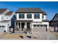 Beautiful two-story home with a gray roof, gray garage, manicured lawn and charming front porch at 1571 Poplar Dr, Erie, CO 80516