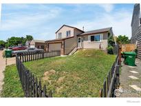 Charming two-story home featuring a well-maintained front yard with a black picket fence and a detached garage at 1687 Ensenada Way, Aurora, CO 80011