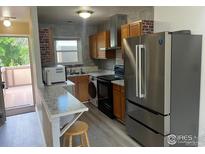 A modern kitchen features stainless steel appliances, granite counters, and ample wooden cabinetry at 225 E 8Th Ave # B11, Longmont, CO 80504