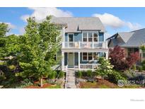 Inviting two-story home features a charming porch, second story balcony, and lush landscaping at 2856 Shadow Lake Rd, Lafayette, CO 80026