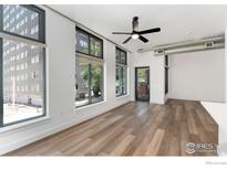 Bright living room featuring large windows, hardwood floors, and modern ceiling fan at 3100 Huron St # 1D, Denver, CO 80202
