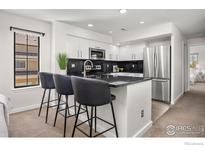 Modern kitchen featuring white cabinets, granite countertops, stainless steel appliances, and breakfast bar at 5904 Gunbarrel Ave # B, Boulder, CO 80301