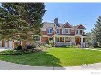 Charming two-story home showcasing a spacious front porch, manicured lawn, and tasteful stone accents at 6487 Cherry Ct, Niwot, CO 80503