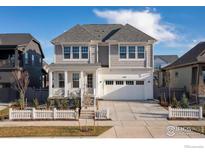 Charming two-story home featuring a covered porch, white picket fence, and an attached two-car garage at 1582 Ash Dr, Erie, CO 80516