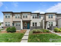 Charming townhome featuring tidy landscaping and a welcoming teal front door at 4774 Kittredge St, Denver, CO 80239