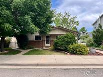 Charming single-story home with brick accents, a well-manicured lawn, and mature landscaping in a suburban neighborhood at 1212 Grant Ave, Louisville, CO 80027