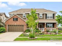 Beautiful two-story home with brick and siding, professionally landscaped yard and a covered front porch at 15810 E Tall Timber Ln, Parker, CO 80134