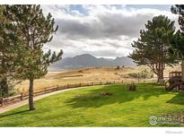 Sprawling green backyard featuring lush lawn, wood fence and stunning mountain views in the distance at 1624 Bradley Ct, Boulder, CO 80305