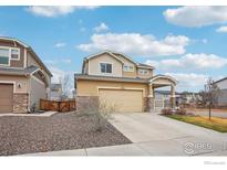 Two-story home with beige siding, stone accents, and a covered front porch against a blue sky at 17995 E 107Th Pl, Commerce City, CO 80022
