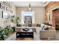 Bright living room features exposed brick, large windows, modern lighting, and comfortable sectional seating at 2500 Walnut St # 201, Denver, CO 80205