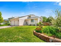 Charming two-story home with well-maintained lawn, landscaped flower bed, and attached two car garage at 7414 Benton St, Arvada, CO 80003
