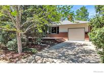 Charming single-story home featuring a brick facade, attached garage, mature trees, and a welcoming front deck at 1245 Claremont Dr, Boulder, CO 80305