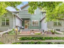 Charming home featuring green siding, a cozy front patio, and a picturesque white picket fence at 179 Rendezvous Dr, Lafayette, CO 80026