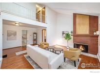 Bright living room boasts a brick fireplace, hardwood floors, and ample natural light from the large windows at 1945 Yank Ct, Golden, CO 80401