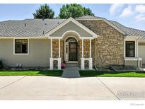 Charming home featuring a stone facade and covered entryway with a well-maintained lawn at 203 Springs Dr, Louisville, CO 80027