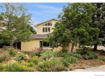 Inviting yellow home showcasing vibrant landscaping and mature trees in a picturesque setting at 2085 Alpine Dr, Boulder, CO 80304