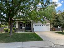 Charming home with a well-maintained front yard, covered porch, and attached two-car garage at 669 Timothy Dr, Longmont, CO 80503