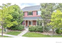 Inviting two-story home featuring a charming front porch, well-maintained landscaping, and mature trees at 8367 Devinney St, Arvada, CO 80005