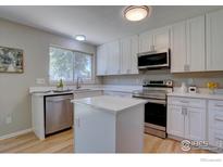 Modern kitchen features white cabinets, stainless steel appliances, quartz counters, and a convenient center island at 13382 Franklin St, Thornton, CO 80241