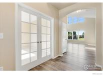 Inviting foyer with hardwood floors, arched doorway, and glass panel french doors at 17216 E Trailmaster Dr, Parker, CO 80134