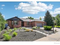 Charming brick home featuring a manicured front yard with mature trees and an inviting walkway at 1806 Crestone Ct, Longmont, CO 80504