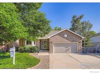 Charming brick home featuring a manicured lawn, mature trees, and a two-car garage at 2615 Falcon Dr, Longmont, CO 80503