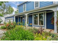 Charming blue two-story home with beautiful landscaping, lush greenery, and blooming flowers at 515 W Fir Way, Louisville, CO 80027