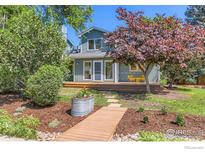 Charming home featuring a wooden deck with yellow chairs and beautifully landscaped yard with a wooden walkway at 725 Union Ave, Boulder, CO 80304