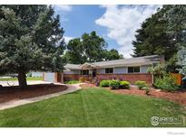Charming ranch-style home with mature trees, green lawn, and inviting brick walkway at 7459 Mount Meeker Rd, Longmont, CO 80503