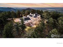 Stunning aerial view of a multi-level mountain home surrounded by lush trees and scenic landscape at 90 Hawk Ln, Boulder, CO 80304