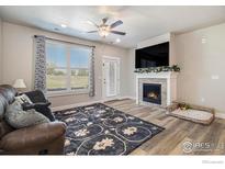 Cozy living room features a fireplace, ceiling fan, and natural light from the large window at 285 High Point Dr # H-104, Longmont, CO 80504