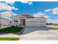 Charming single-story home boasts a three-car garage and well-manicured front yard with blue sky at 338 Lemonade Dr, Berthoud, CO 80513