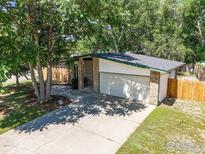 Home exterior showcases a brick facade, a two-car garage, mature trees, and a quaint walkway leading to the entrance at 603 Hilltop St, Longmont, CO 80504
