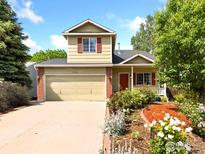 Charming two-story home with attached garage and beautifully landscaped front yard with colorful flowers at 1026 Red Oak Dr, Longmont, CO 80504