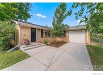 Charming one-story brick home with a well-manicured lawn, mature trees, and a long driveway leading to a single-car garage at 216 Hemlock St, Broomfield, CO 80020
