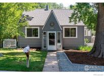Charming gray home featuring updated landscaping, a manicured lawn, and mature trees at 222 Vivian St, Longmont, CO 80501