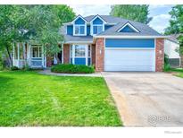 Charming two-story home with a brick facade, blue siding, well-manicured lawn and covered front porch at 2408 Eagleview Cir, Longmont, CO 80504