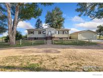 Charming home featuring a gravel drive, a detached garage, and a well-manicured lawn and picket fence at 4700 County Road 38, Platteville, CO 80651