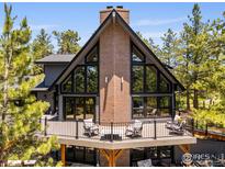Beautiful exterior of home with a large deck, brick chimney, and floor-to-ceiling windows at 8987 Village Pines Cir, Franktown, CO 80116