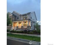 Charming two-story home featuring stone accents, gray siding, and a welcoming front porch with flower boxes at 91 Westerly Blvd, Erie, CO 80516