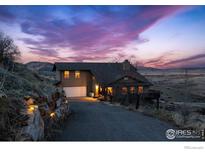 Charming home with a stunning dusk sky, stone retaining wall, and a welcoming driveway at 11730 Pointe View Dr, Longmont, CO 80503