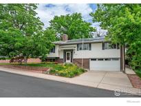 Charming two-story home with mature trees, brick accents, and a well-manicured front yard with fresh green grass at 13313 W Utah Cir, Lakewood, CO 80228