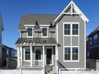 Charming gray two-story home with white trim, a metal roof over the porch, and a picket fence at 138 Westerly Blvd, Erie, CO 80516