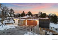 Modern home with a flat roof, sleek lines, wood accents, and a driveway dusted with snow at 2206 Alpine Dr, Boulder, CO 80304