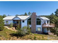 Charming home featuring a stone chimney, large windows, and spacious wooden decks at 237 Puma Dr, Boulder, CO 80302