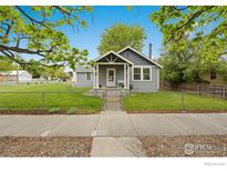 Charming gray home with a welcoming front porch and a well-manicured lawn at 409 Main St, Mead, CO 80542