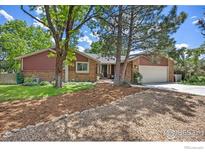 Charming home with brick and wood siding, mature trees, and a well-maintained lawn at 5314 S Youngfield Ct, Littleton, CO 80127
