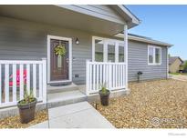 Charming front entrance with a brown door, floral wreath, and nicely landscaped stone at 7840 Cattail Grn, Frederick, CO 80530