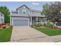 Charming blue two-story home featuring a well-manicured lawn and inviting front porch at 940 Petras St, Erie, CO 80516