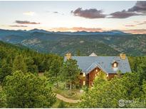Stunning log home with mountain views, mature trees, and a stone tile roof at sunset at 1050 Pine St, Boulder, CO 80302